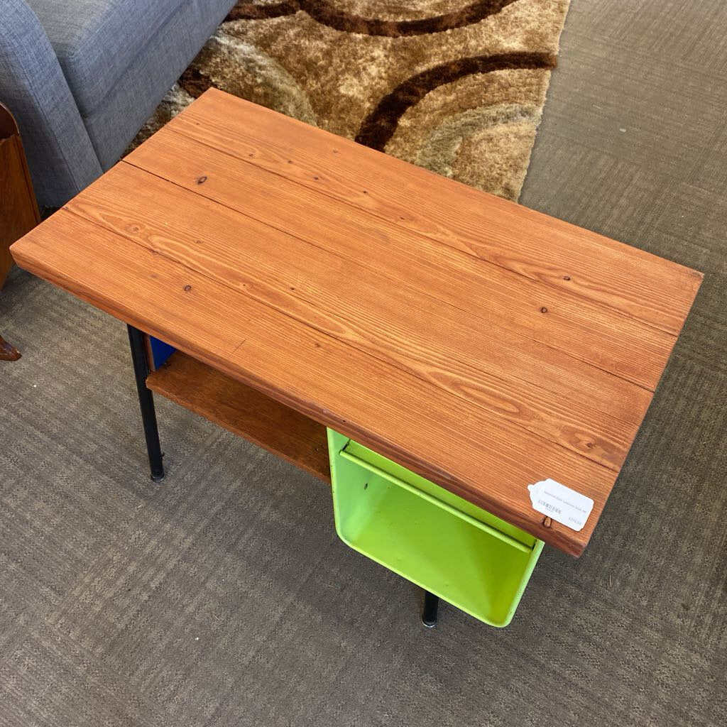 Wooden desk with a green storage bin on a carpeted floor