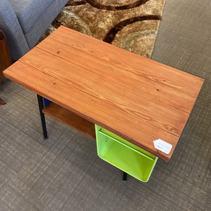 Wooden desk with a green storage bin on a carpeted floor