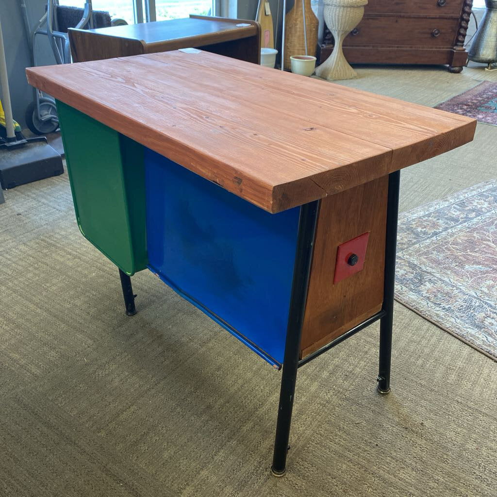 Wooden desk with colorful side panels on a carpeted floor