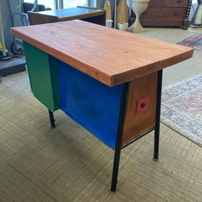 Wooden desk with colorful side panels on a carpeted floor