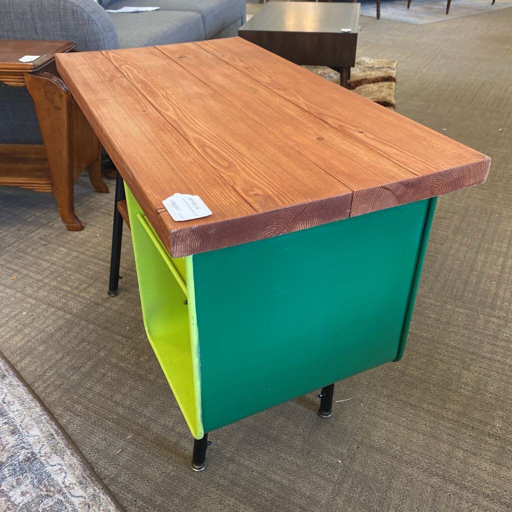 Wooden table with green base on a carpeted floor