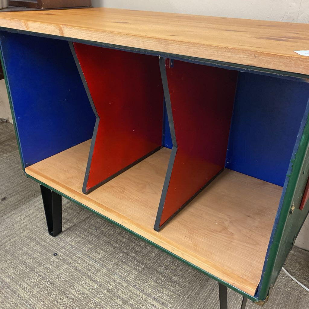 Wooden desk with blue and red interior on a carpeted floor