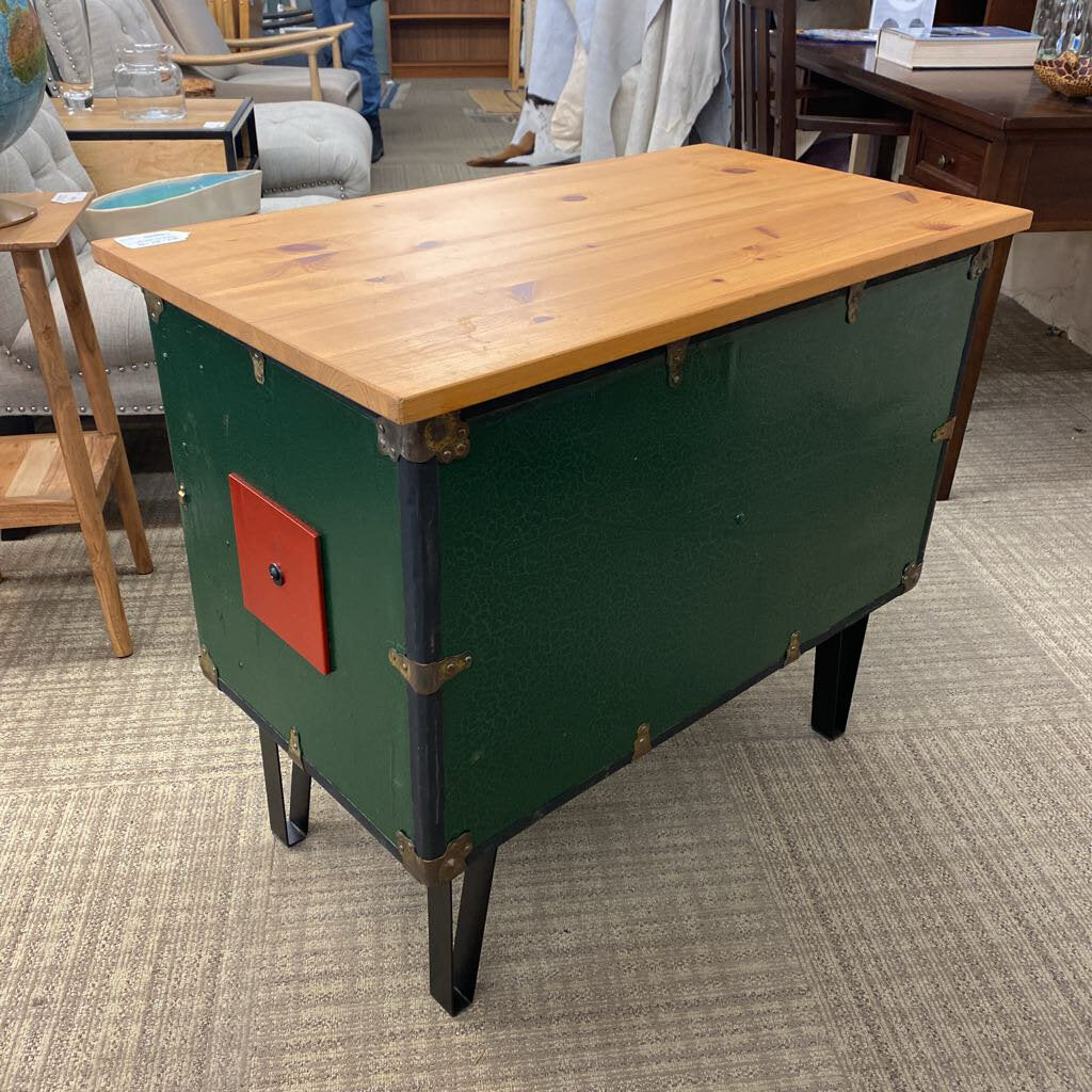 Green metal table with a wooden top on a carpeted floor