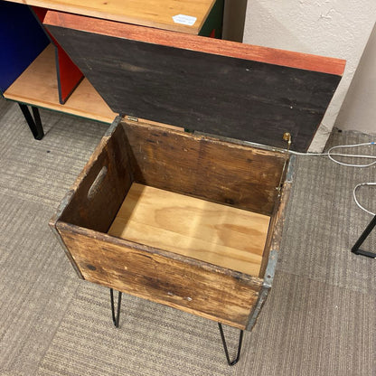 Wooden box with metal legs on a carpeted floor