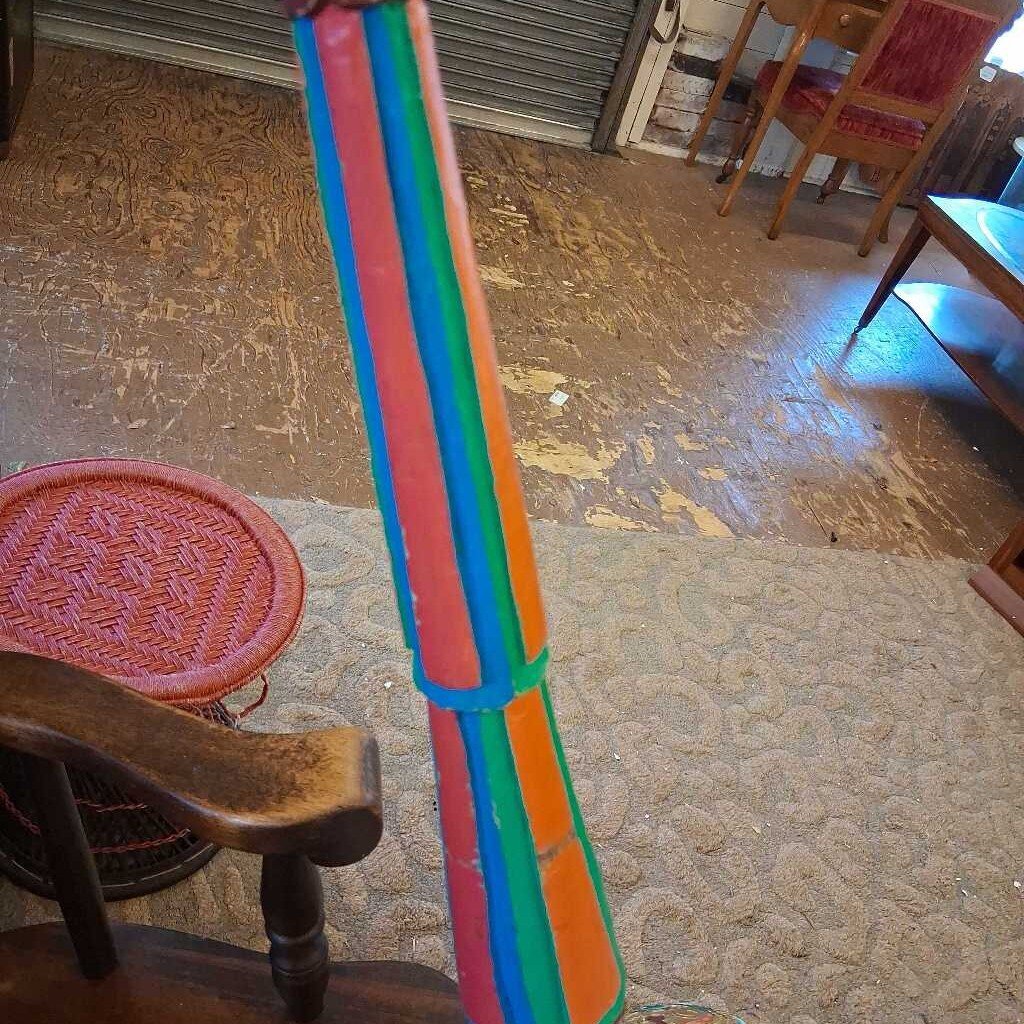 Colorful broom leaning against a chair on a textured floor.