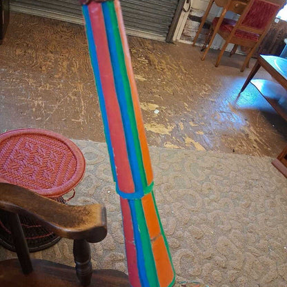 Colorful broom leaning against a chair on a textured floor.