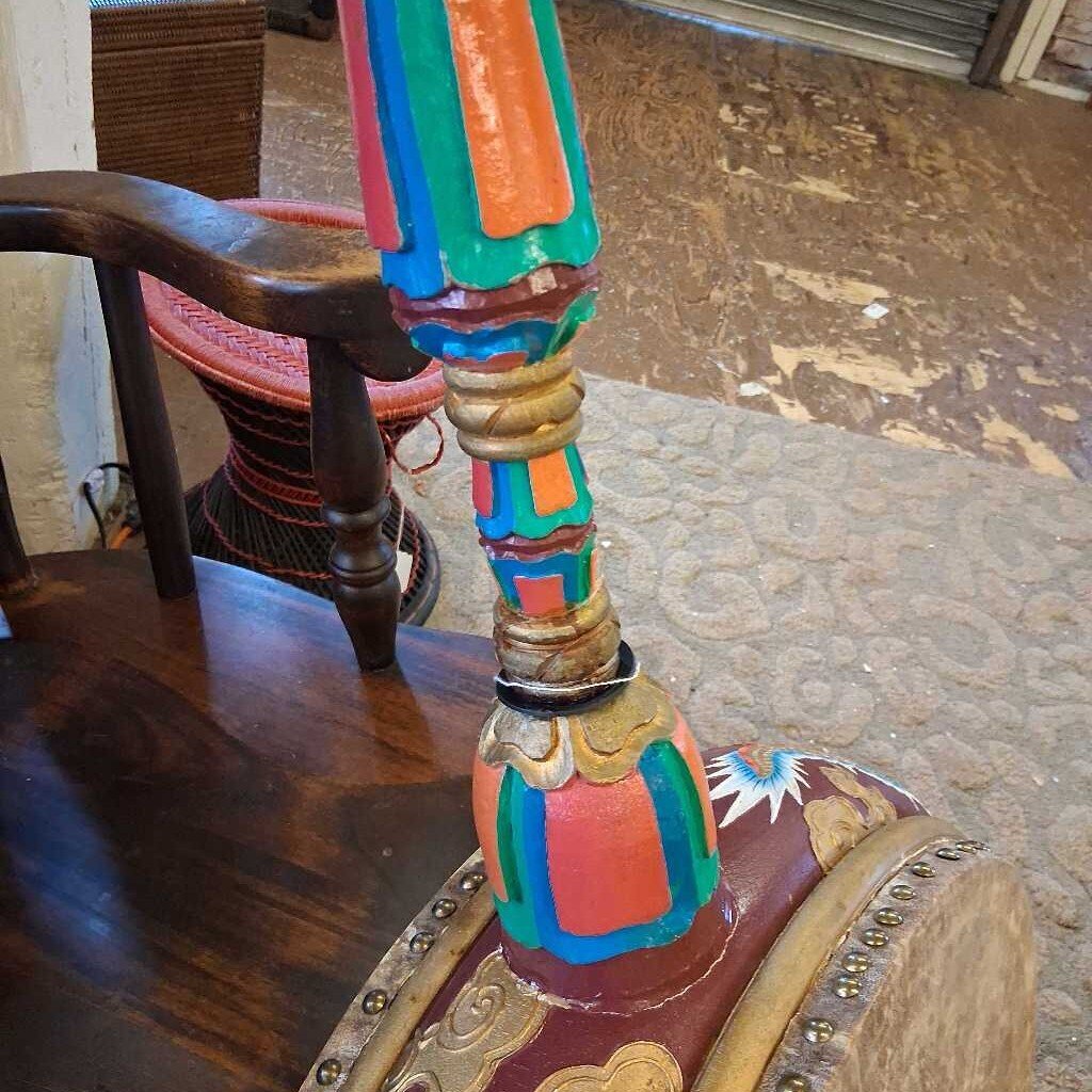 Colorful wooden chair with intricate designs on a carpeted floor.