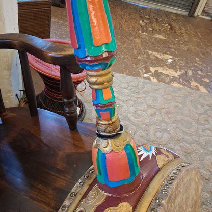 Colorful wooden chair with intricate designs on a carpeted floor.