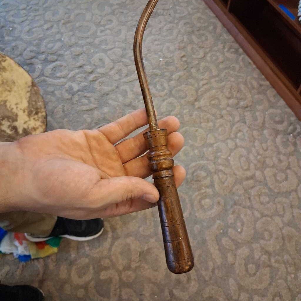 Hand holding a wooden tool against a textured wall background