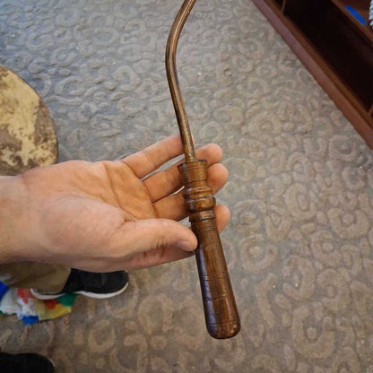 Hand holding a wooden tool against a textured wall background
