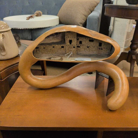 Wooden sculpture of a snake-like creature on a wooden table with a blurred background