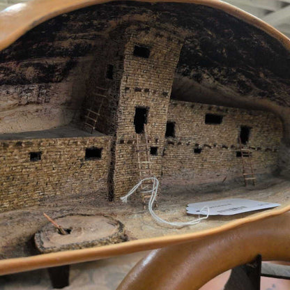 Model of a stone building with a tag attached, possibly in an indoor setting.