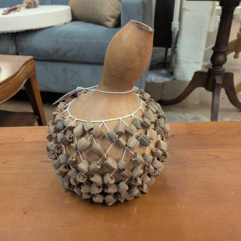 Decorative gourd with netting on a wooden surface in an indoor setting