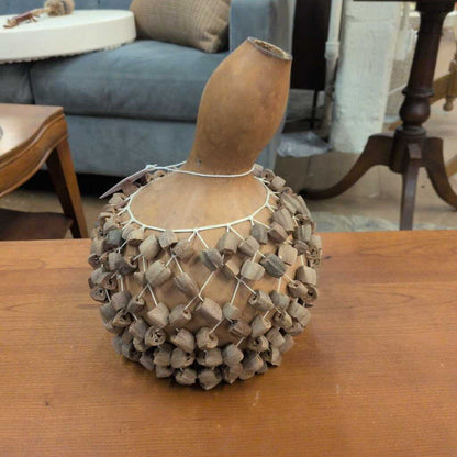 Decorative gourd with netting on a wooden surface in an indoor setting