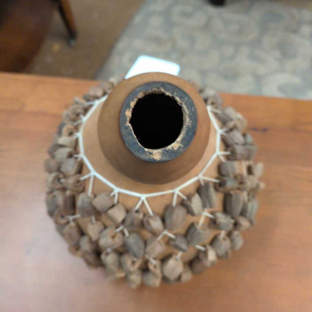 Terra cotta vase with stone mosaic base on a wooden surface