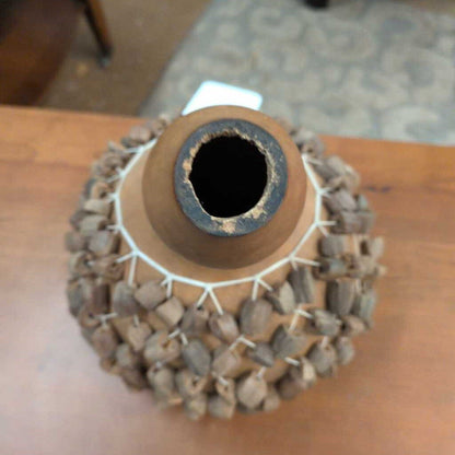 Terra cotta vase with stone mosaic base on a wooden surface