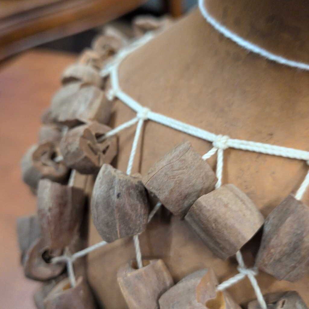 Close-up of a necklace with wooden beads on a mannequin.
