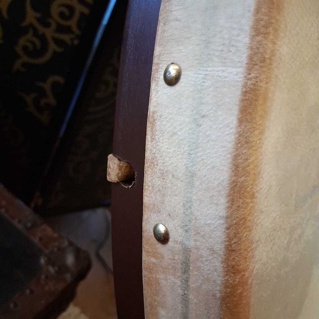 Close-up of a leather belt with a hole and metal buckle.