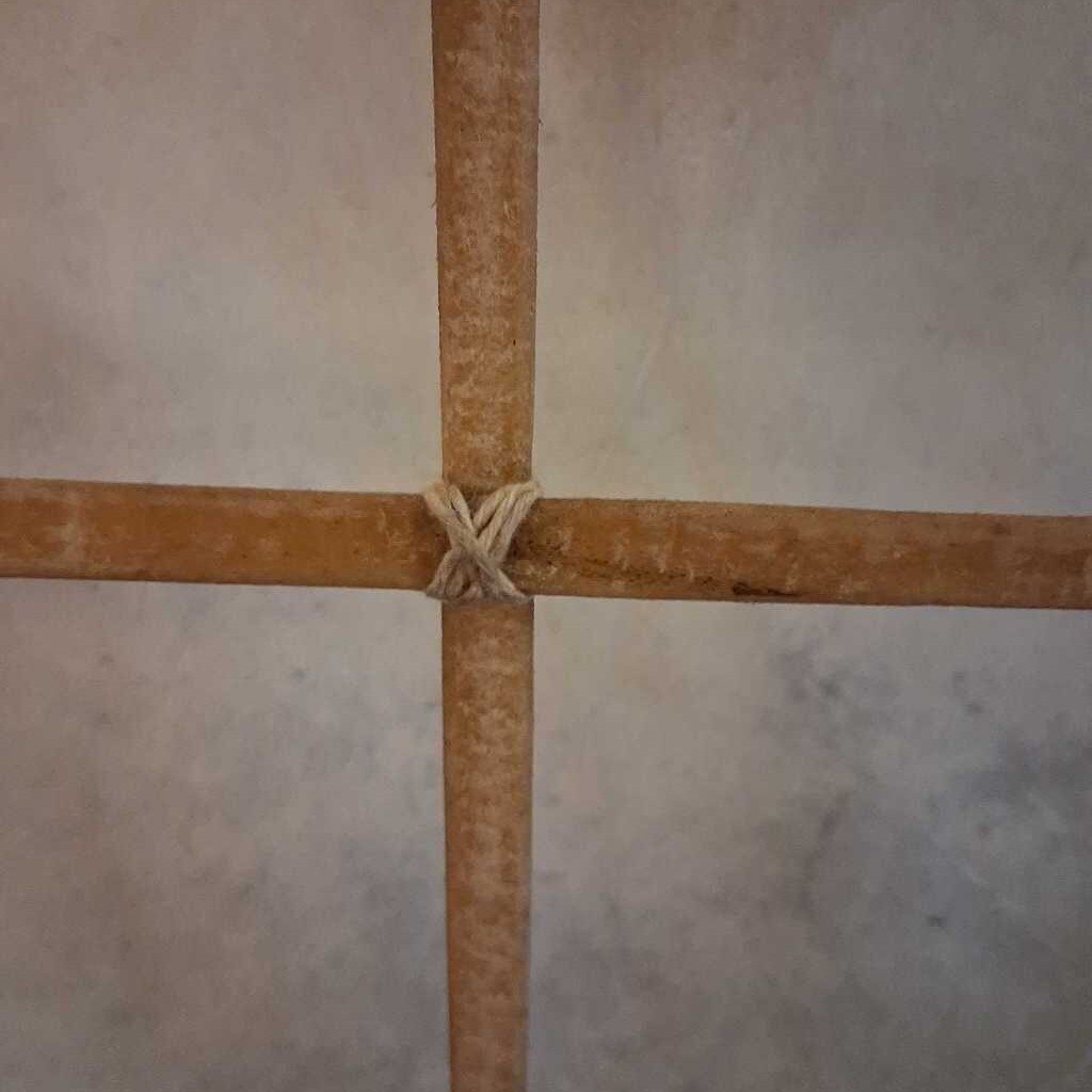 Two wooden sticks tied together on a tiled floor