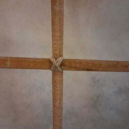 Two wooden sticks tied together on a tiled floor