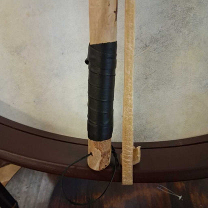 Close-up of a wooden stick with black grip against a textured wall.