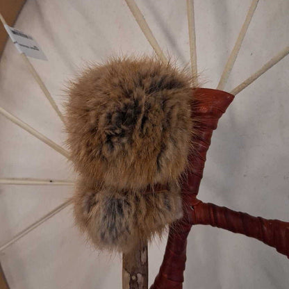 Fur pom-pom attached to a red handle against a white background