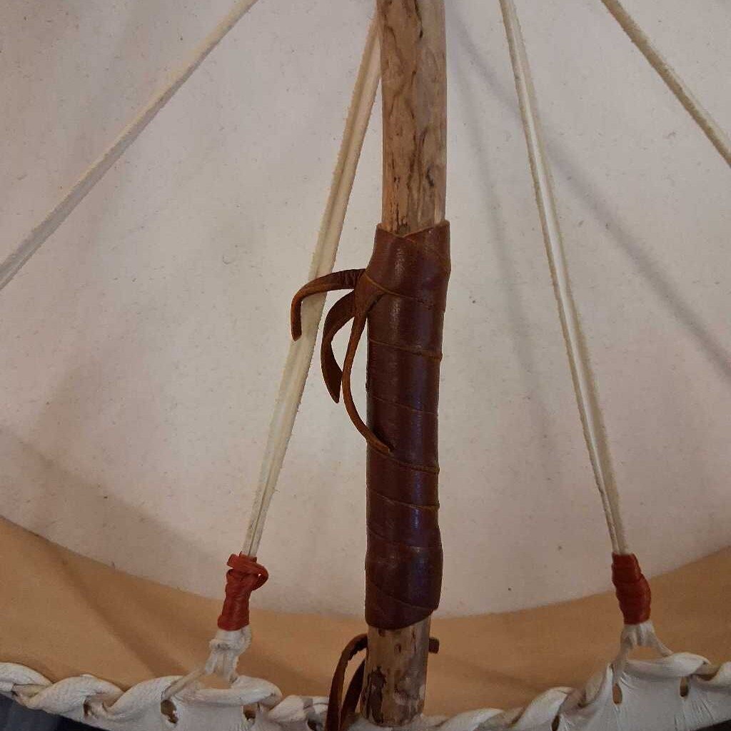 Close-up of a wooden pole with a leather strap inside a tent-like structure.