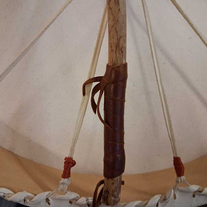 Close-up of a wooden pole with a leather strap inside a tent-like structure.