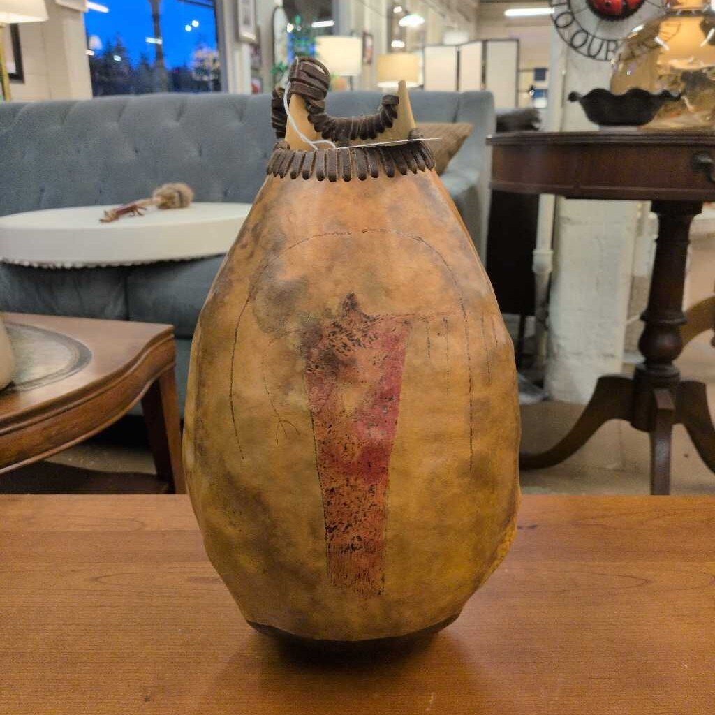 Decorative gourd with rustic design on a wooden table in an indoor setting