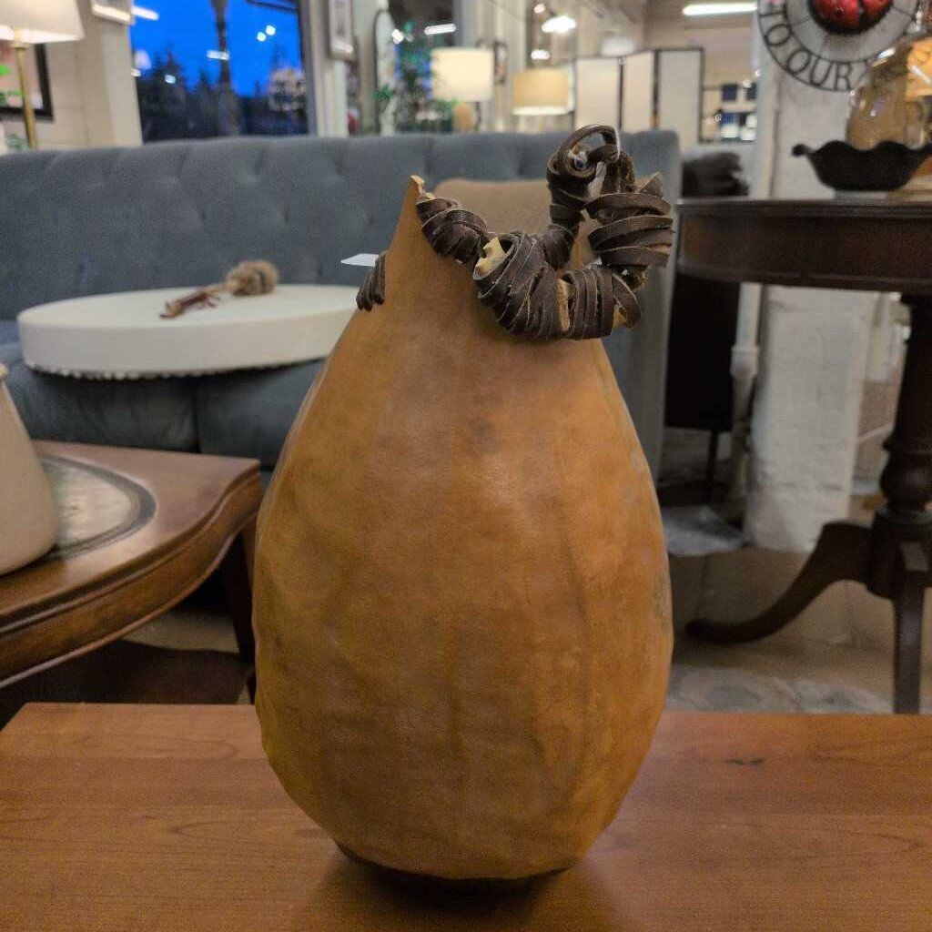 Decorative gourd with woven top on a wooden table in a store setting