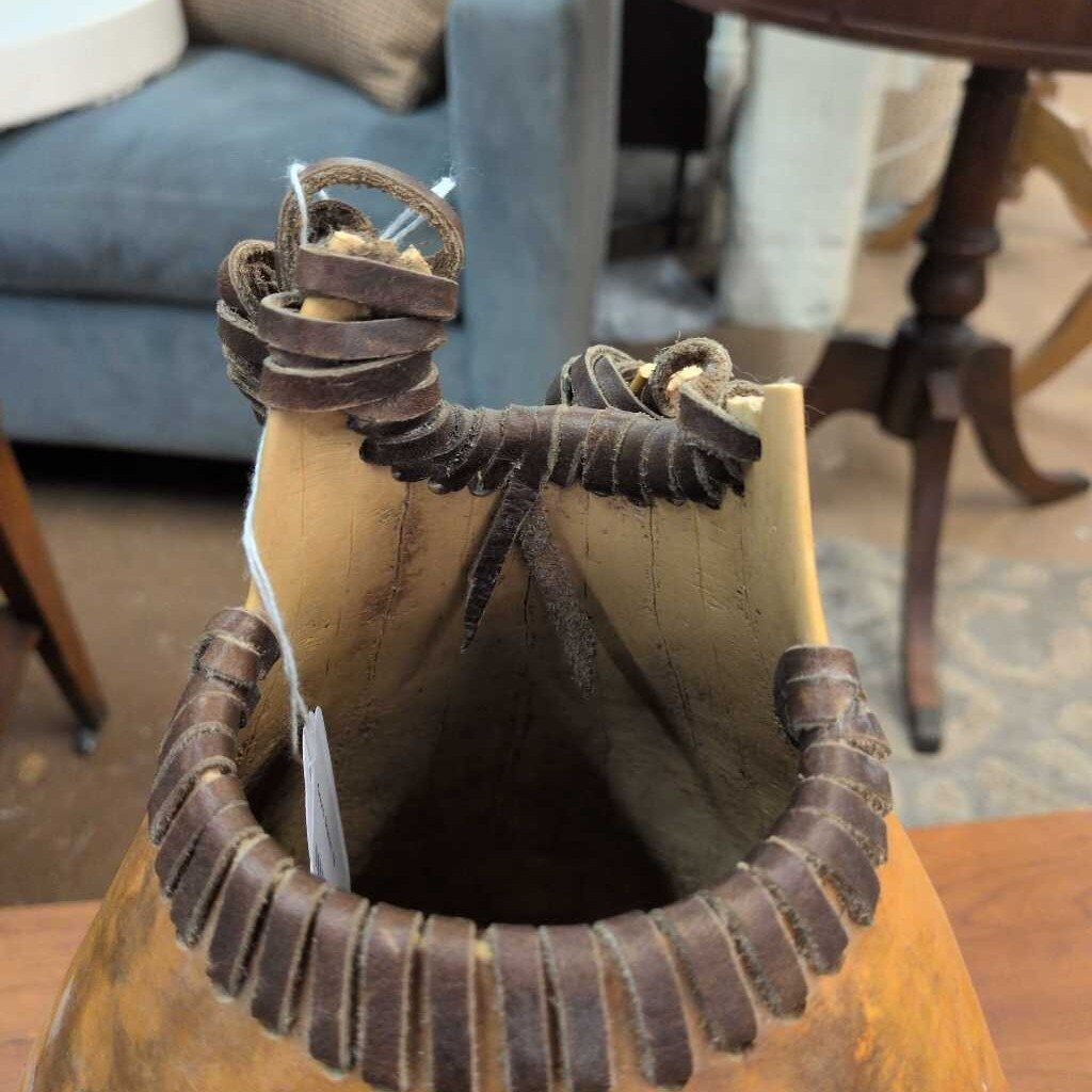 Brown leather bag with decorative straps on a wooden surface