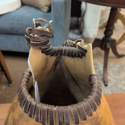 Brown leather bag with decorative straps on a wooden surface