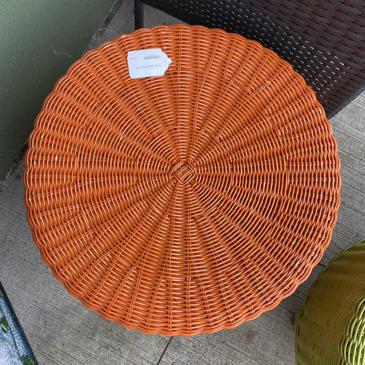 Round woven orange ottoman on a concrete floor