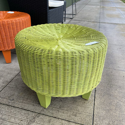 Green woven stool on a patio with an orange stool in the background