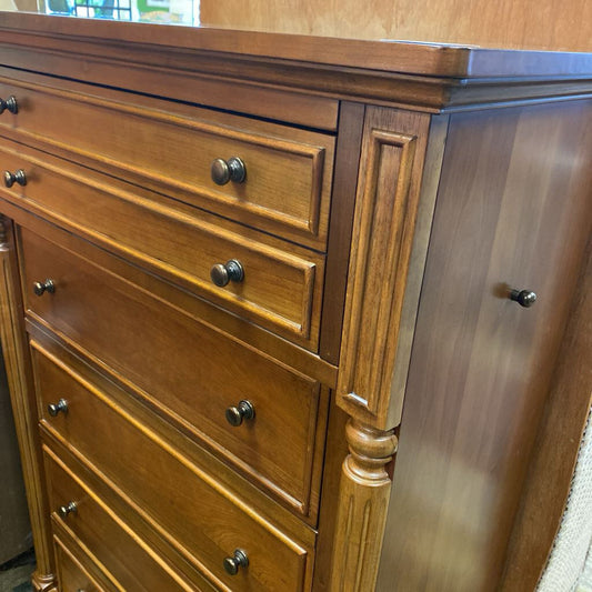 Wooden dresser with multiple drawers and a metallic surface.