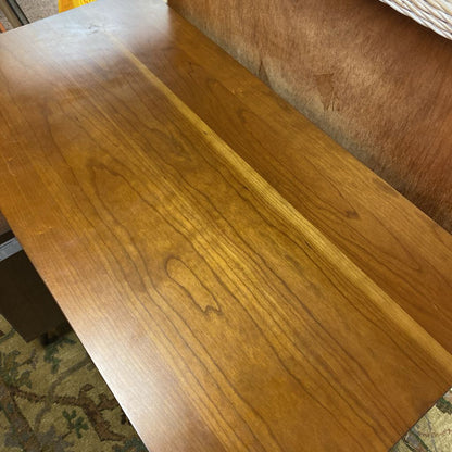Wooden table with a brown finish on a carpeted floor