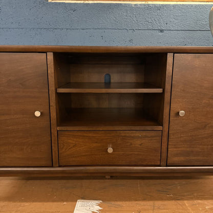 Wooden cabinet with open shelf and closed doors against a blue wall.