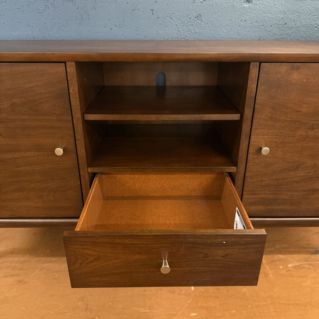 Wooden cabinet with an open drawer against a blue wall.