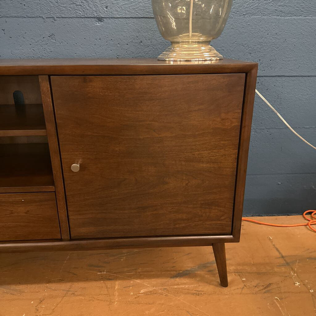 Wooden sideboard with a glass lamp against a blue wall.