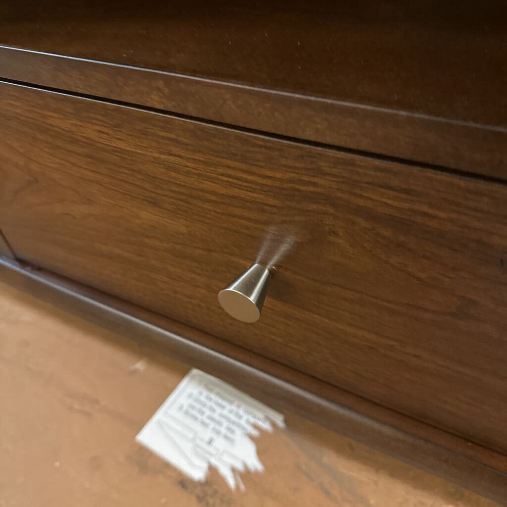 Close-up of a wooden drawer with a metal handle on a reflective surface.