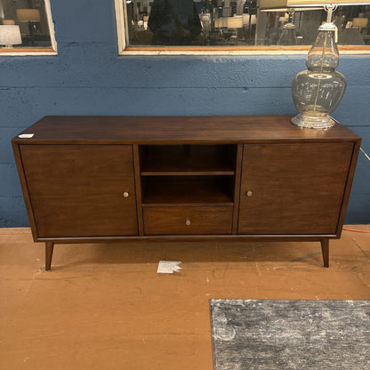 Wooden sideboard against a blue wall with a lamp on top
