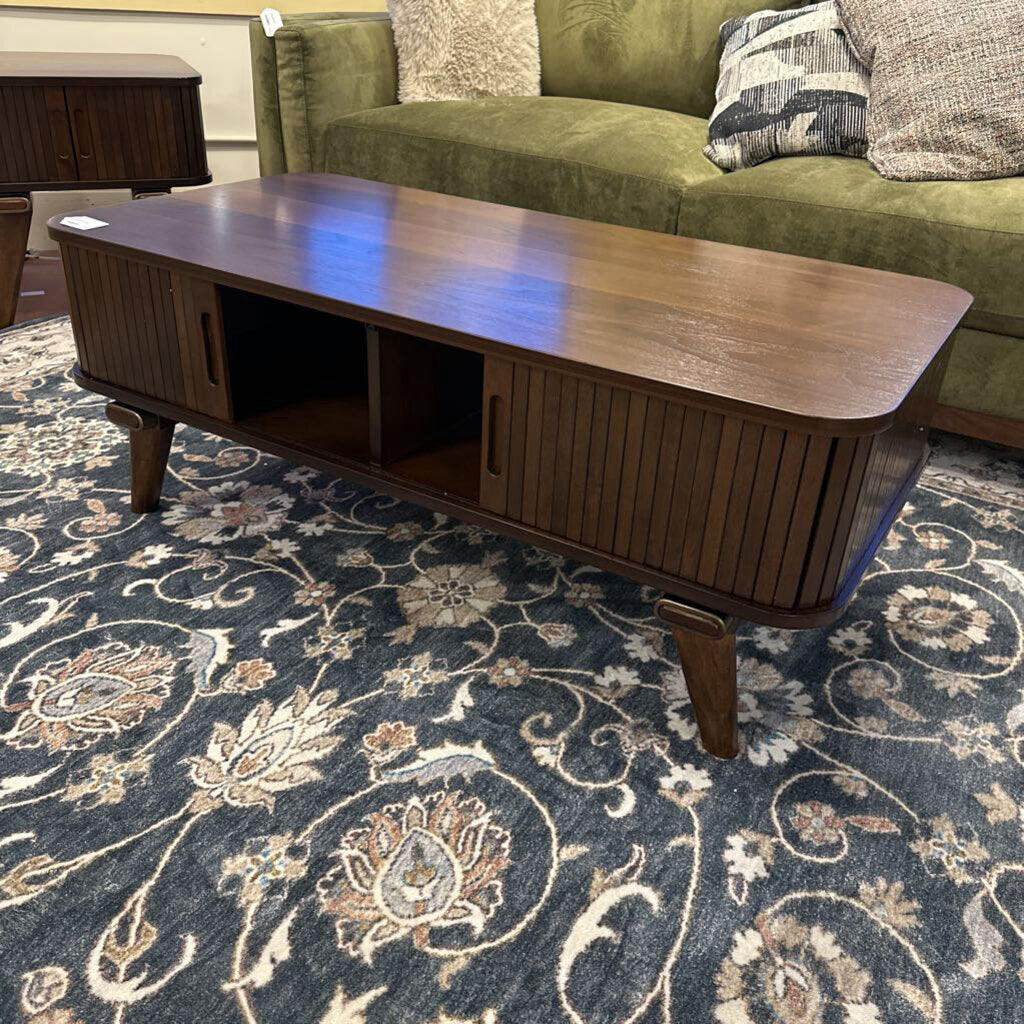 Wooden coffee table in front of a green sofa on a patterned rug