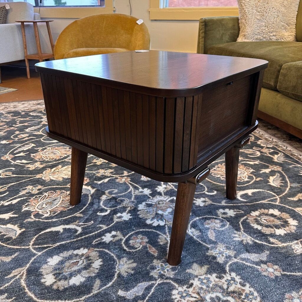 Wooden coffee table in a living room setting with a patterned rug and furniture.