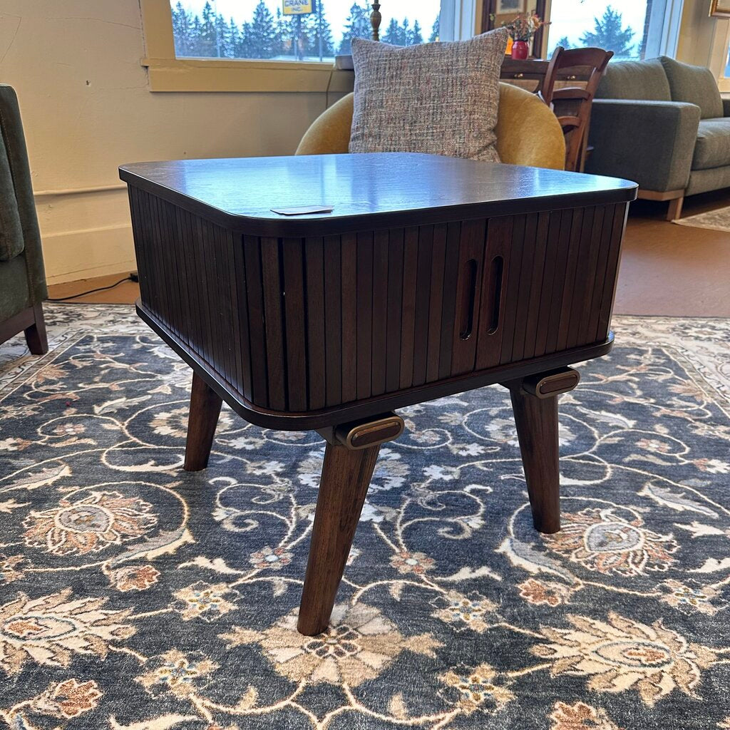 Wooden coffee table in a living room setting with a patterned rug and furniture.