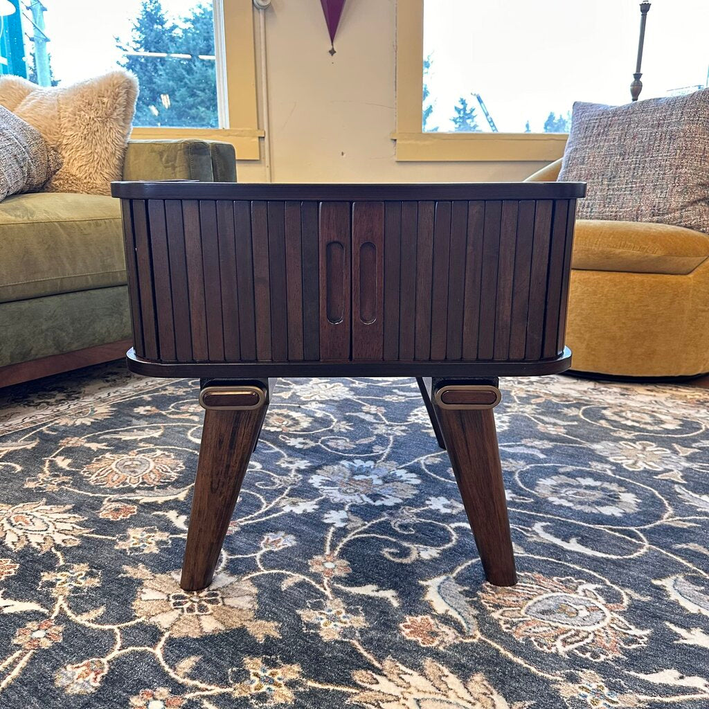 Wooden coffee table in a living room with a patterned rug and couches.