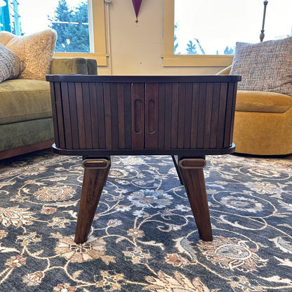 Wooden coffee table in a living room with a patterned rug and couches.