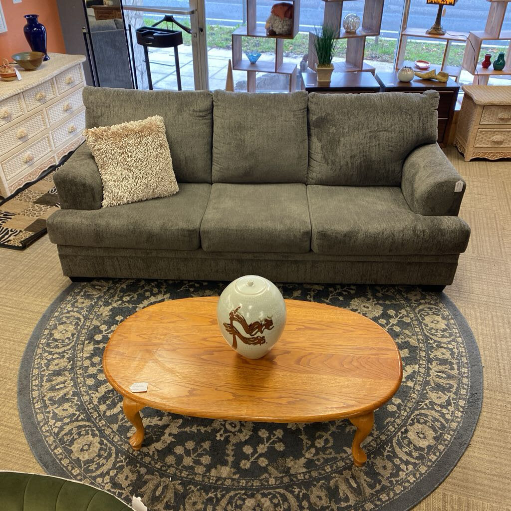 Gray sofa with a wooden coffee table and decorative vase on a patterned rug in a room.