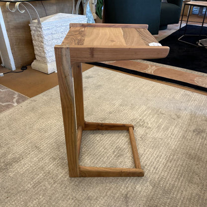 Wooden side table on a carpeted floor with a blurred background