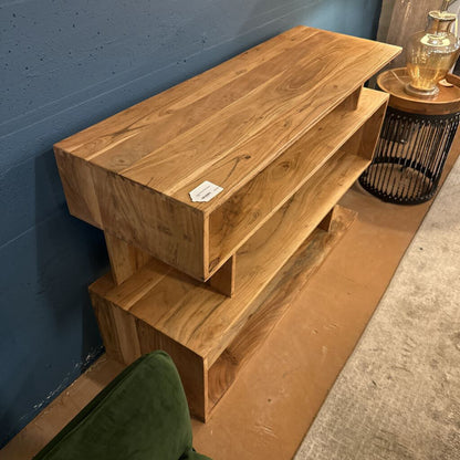 Wooden shelf against a blue wall with a lamp on top