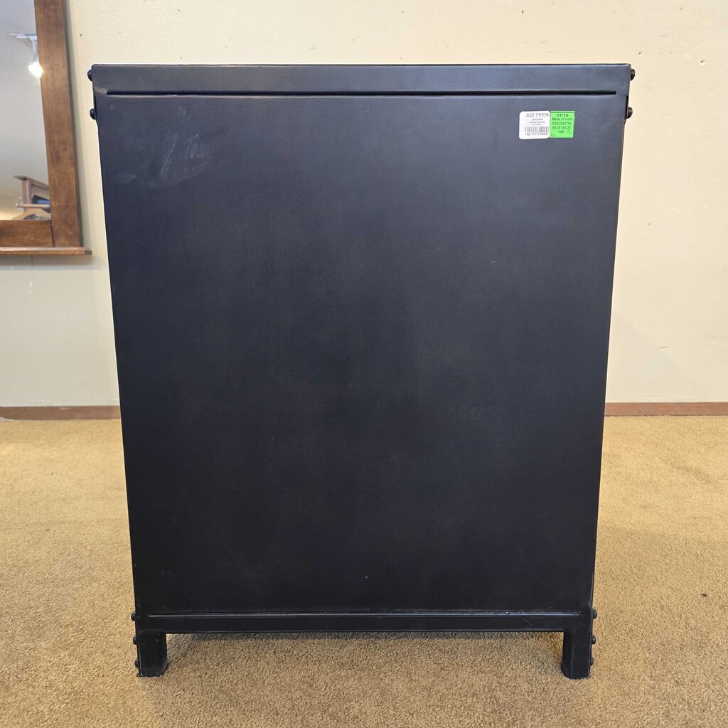 Black refrigerator on a beige carpeted floor with a white wall in the background